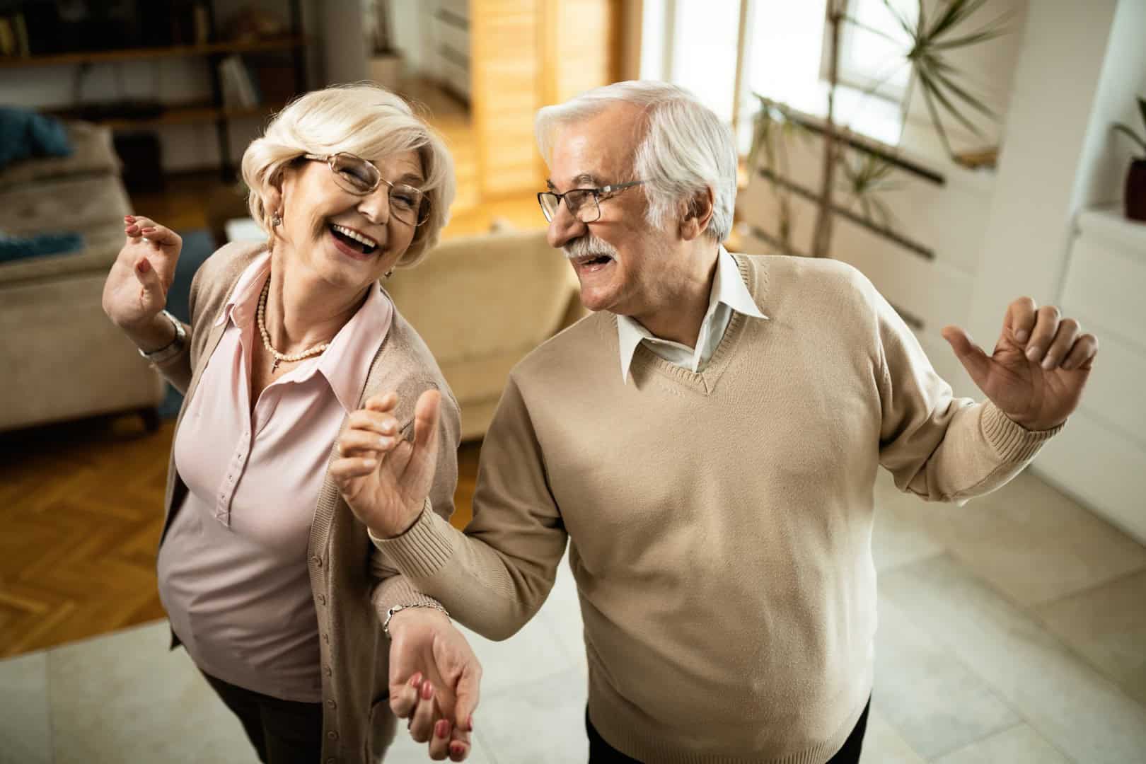 Cheerful senior couple dancing and having fun at home.